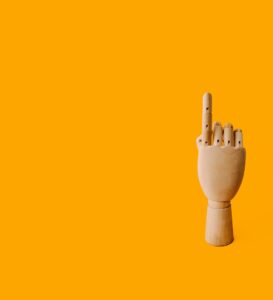 beige wooden hand sculpture with orange background